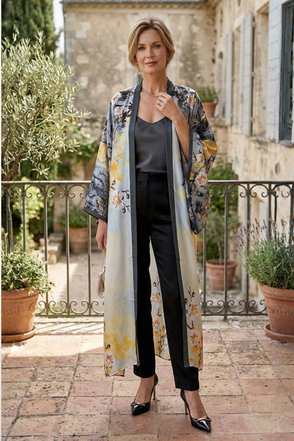 Femme portant un cardigan kimono aux motifs floraux, en soie, avec un pantalon noir et des escarpins, dans un décor