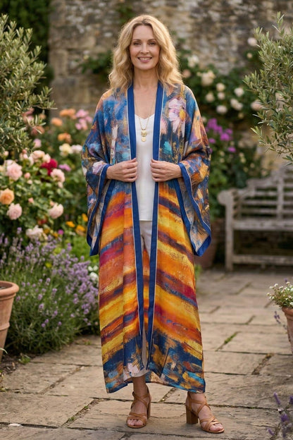 Femme souriante portant un cardigan kimono aux couleurs vives, dans un jardin fleuri avec des roses et des lavandes