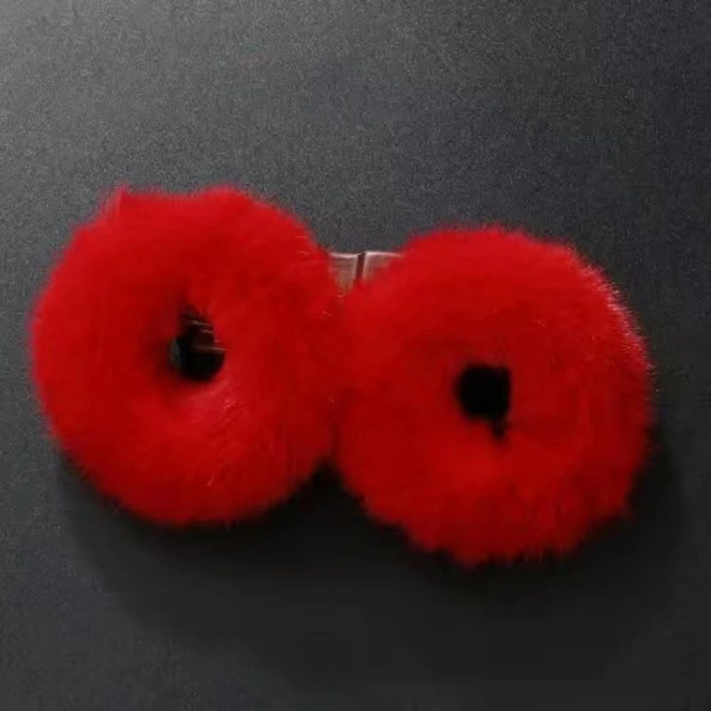 Accessoire en fourrure rouge vif en forme de cercles, posé sur un fond noir lisse