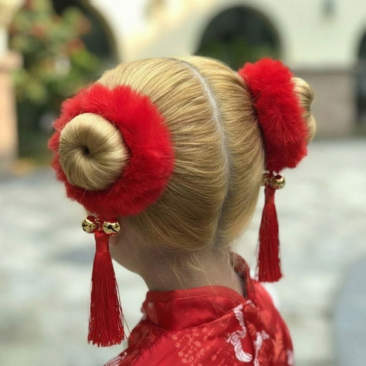 Coiffure traditionnelle avec deux chignons blonds ornés de pompons rouges et de glands dorés, vêtue d'un kimono rouge