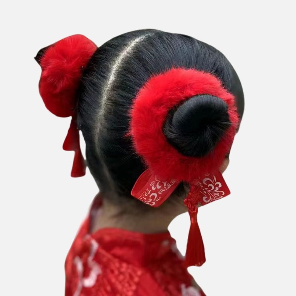 Coiffure traditionnelle avec un chignon noir orné de pompons rouges et de rubans décoratifs