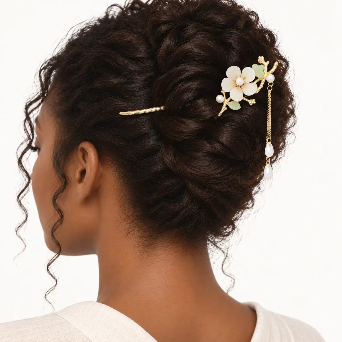 Chignon retenu par une épingle dorée ornée d’une fleur.