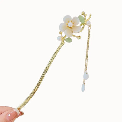 Épingle dorée ornée d’une fleur, présentée seule.