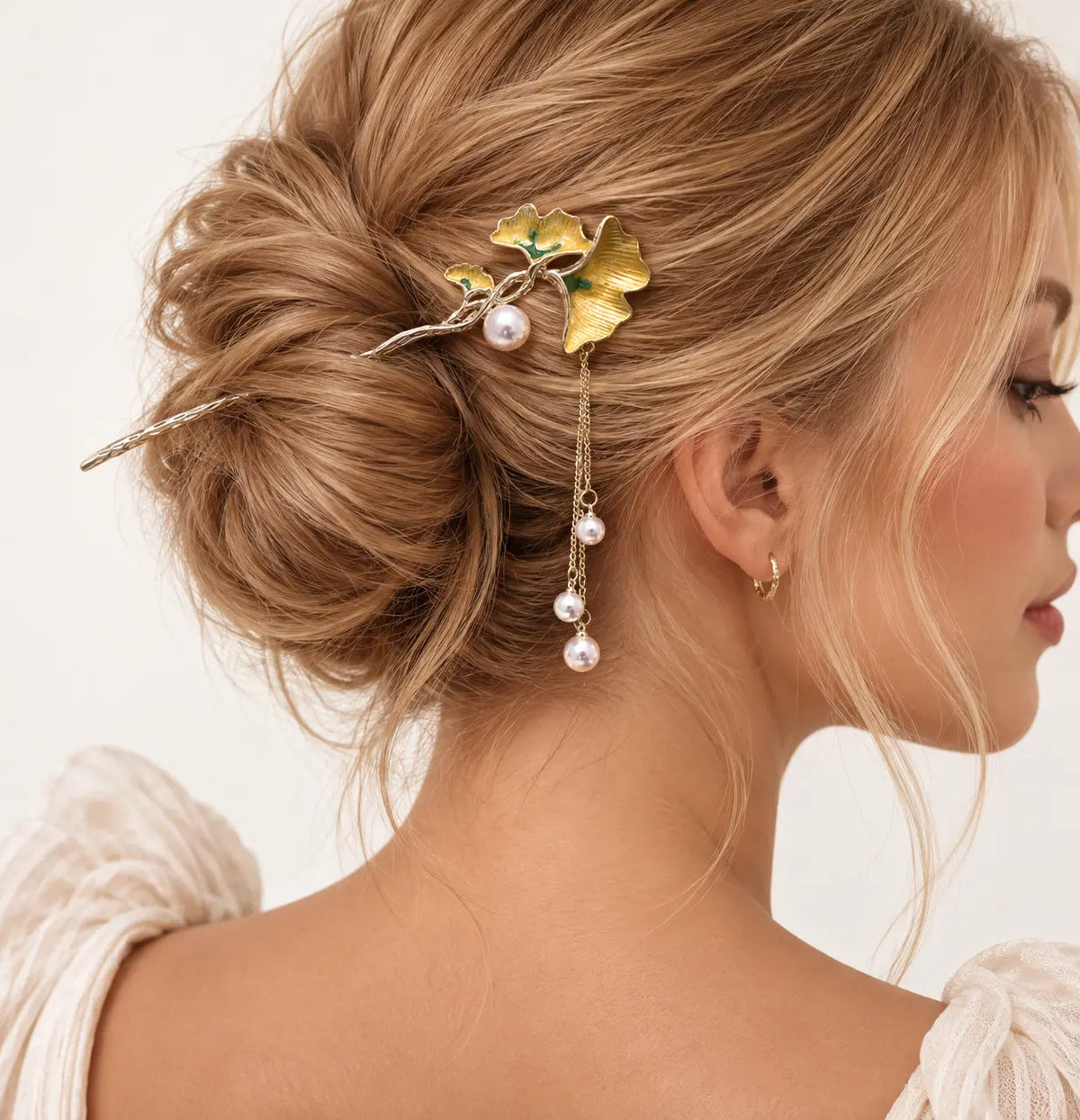 Chignon agrémenté d’une épingle à feuilles dorées et perles.