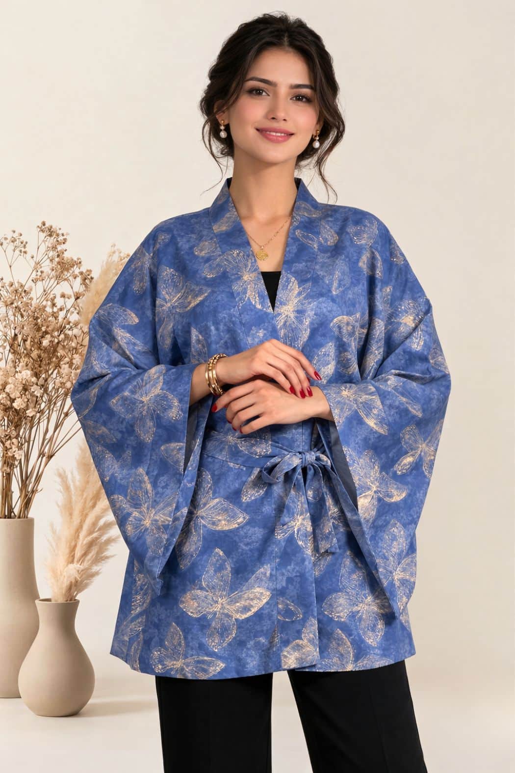 Haori bleu avec motifs de papillons dorés, porté par une femme souriante, décoré de fleurs séchées en arrière-plan