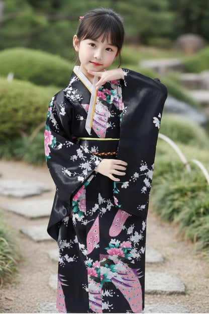 Fille en kimono noir orné de fleurs roses et blanches, posant avec élégance dans un jardin zen