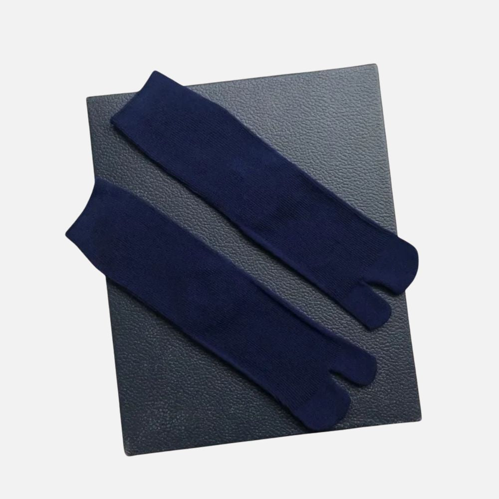 Chaussettes tabi bleu marine posées sur un fond noir, affichant une texture douce et un design traditionnel