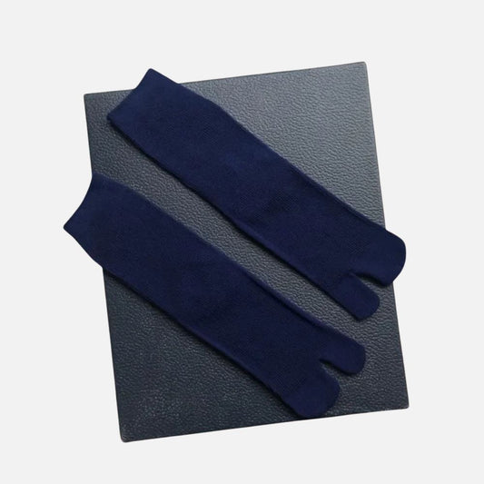 Chaussettes tabi bleu marine posées sur un fond noir, affichant une texture douce et un design traditionnel