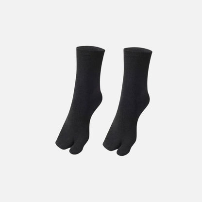 Chaussettes tabi noires en matière douce, avec séparation des orteils, sur fond blanc minimaliste