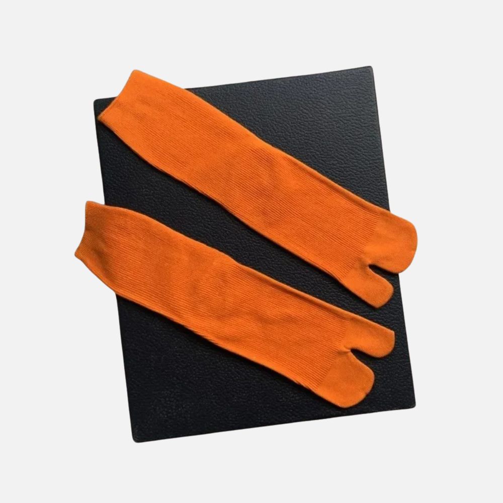 Chaussettes tabi orange posées sur un fond noir, avec une texture douce et un design contemporain
