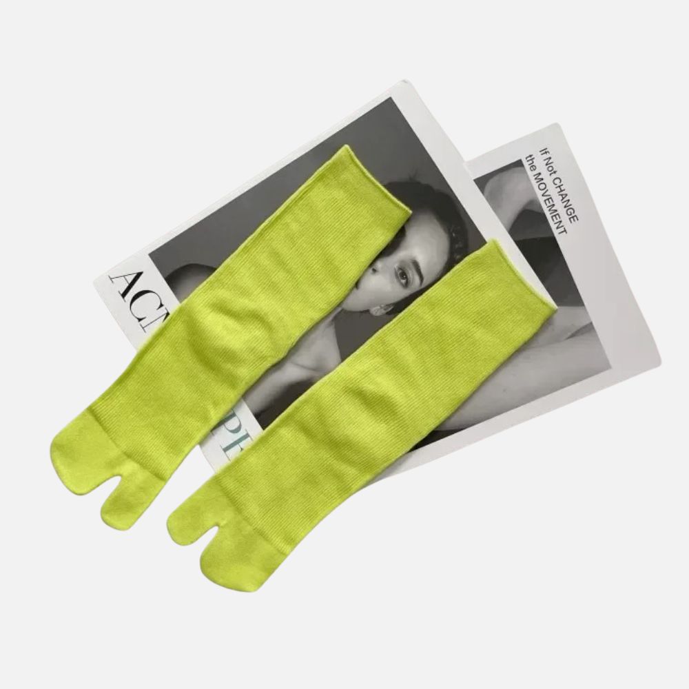 Chaussettes tabi vert citron posées sur un magazine, avec un décor moderne et minimaliste