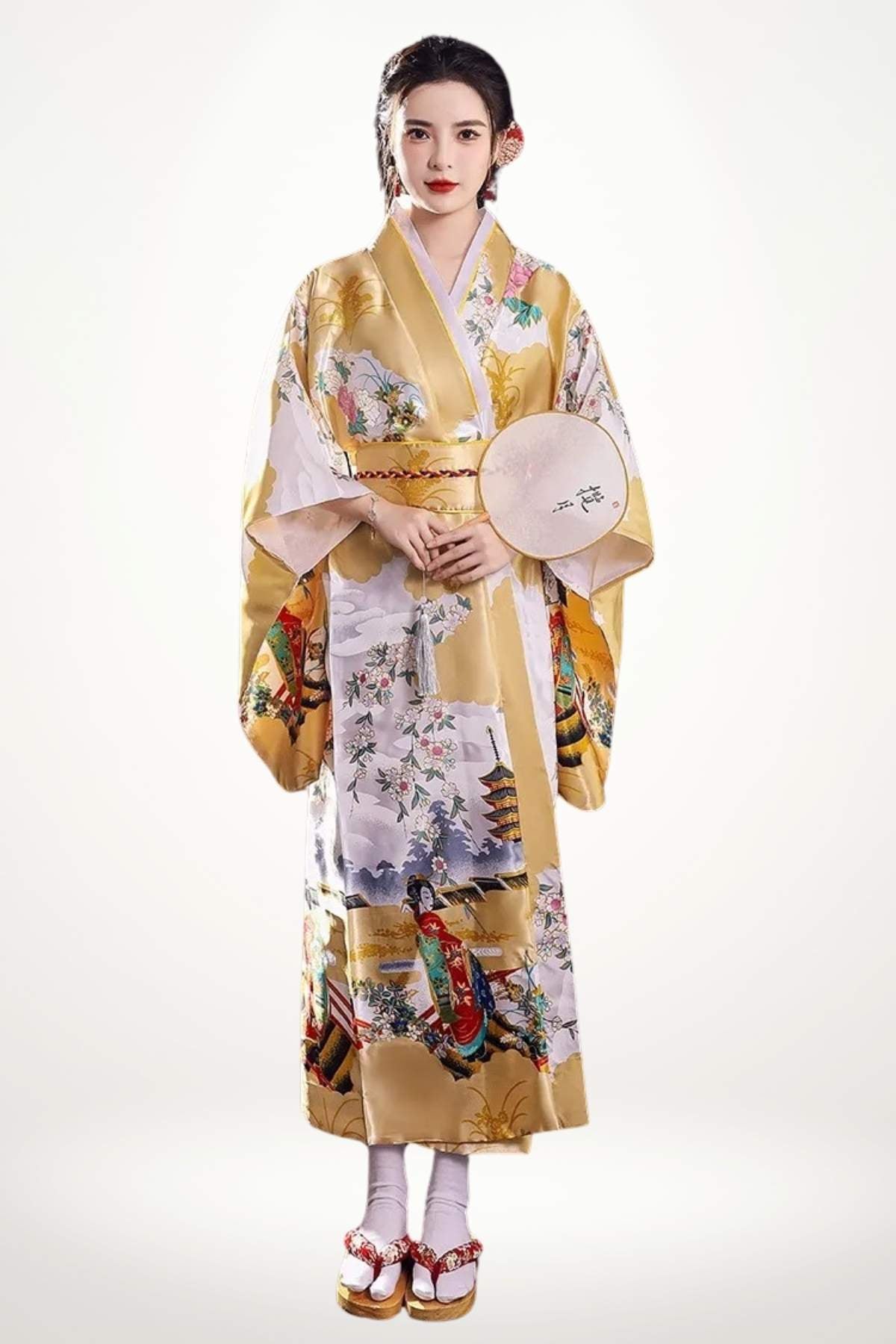 Femme en kimono doré à motifs floraux et scènes japonaises, posant avec un éventail dans un décor neutre