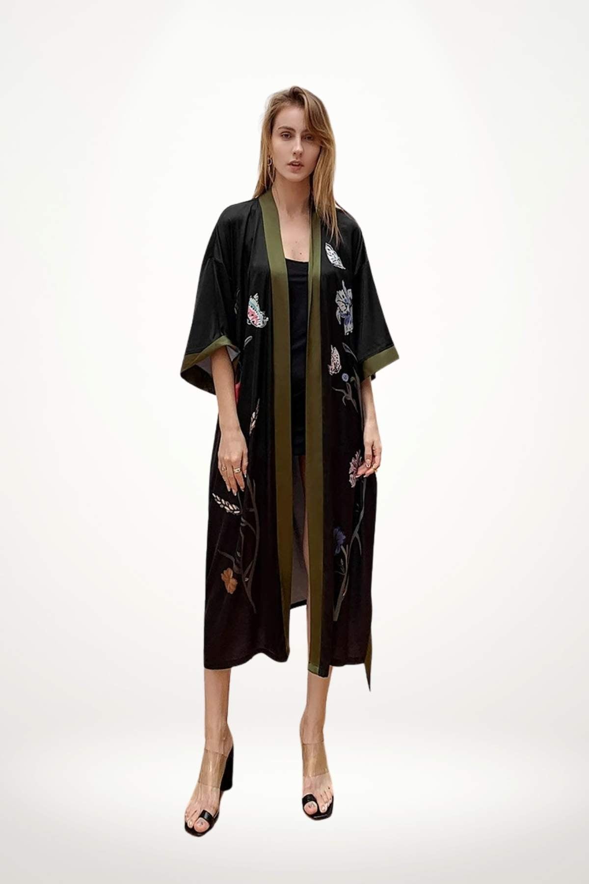 Kimono noir élégant avec des motifs floraux colorés et une bordure verte, porté par une femme debout