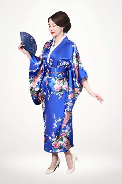 Femme en kimono bleu brillant avec motifs floraux, tenant un éventail, sur fond blanc