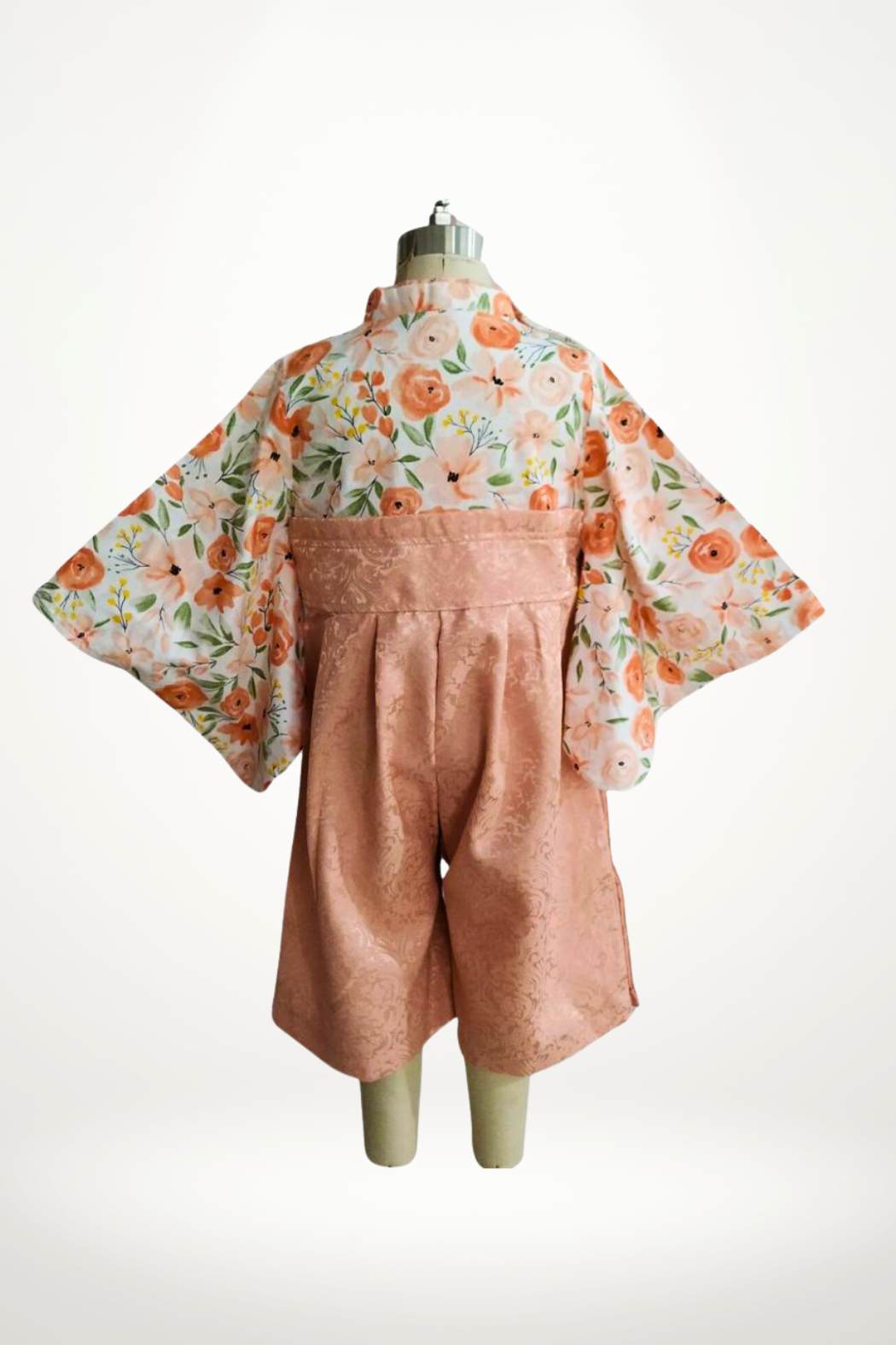 Yukata pour bébé avec des fleurs pêche sur un fond clair, manches larges et ceinture en satin rose