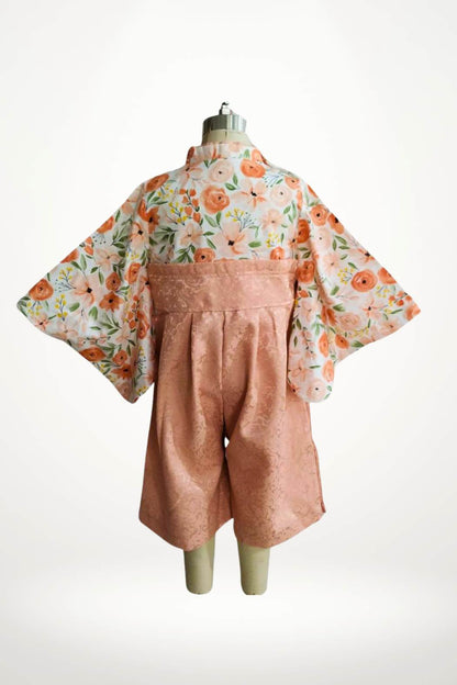 Yukata pour bébé avec des fleurs pêche sur un fond clair, manches larges et ceinture en satin rose