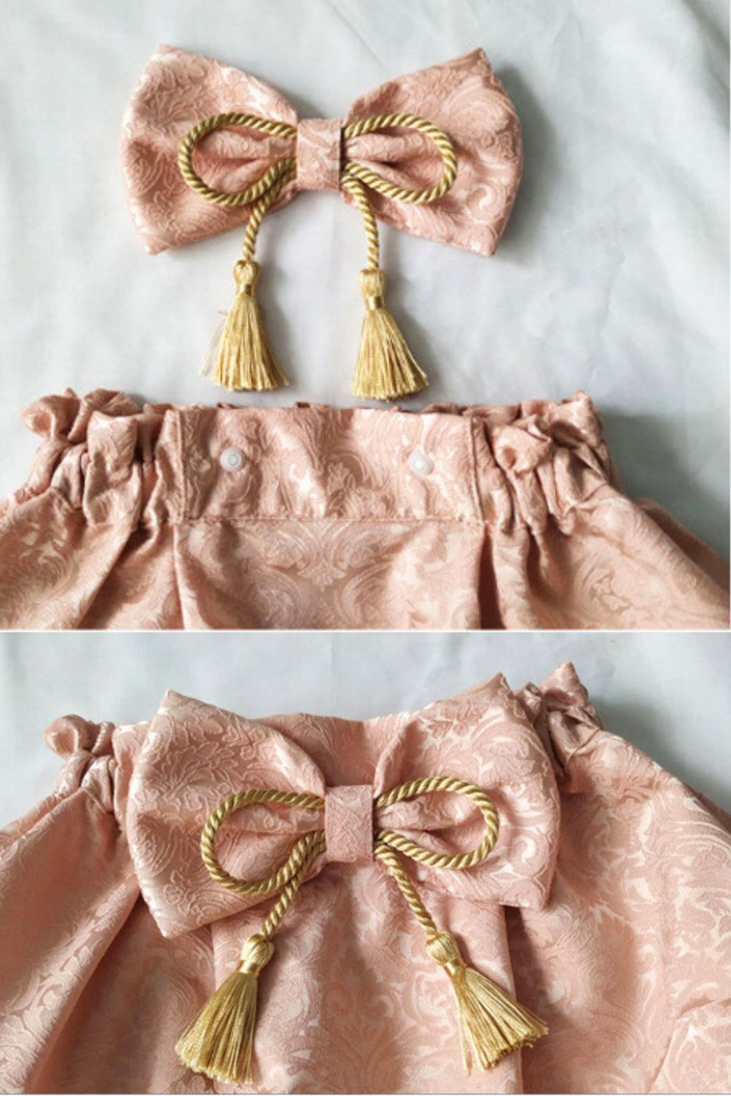 Un nœud en satin rose avec des franges dorées, sur un tissu à motifs délicats, évoquant l'élégance japonaise