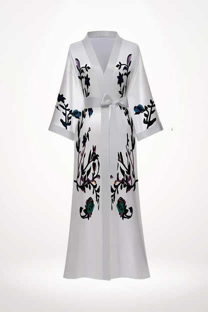 Kimono blanc avec des motifs floraux colorés, ceinturé à la taille, évoquant pureté et élégance délicate