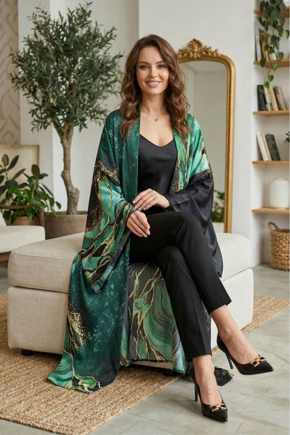 Femme souriante portant un kimono vert aux motifs dorés, assise sur un canapé dans un décor moderne