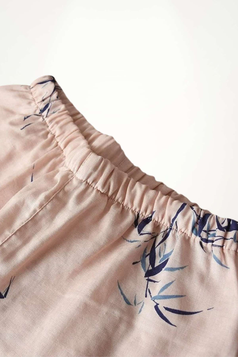 Détail d'un kimono en coton rose avec un motif de feuilles bleues sur le col élastiqué