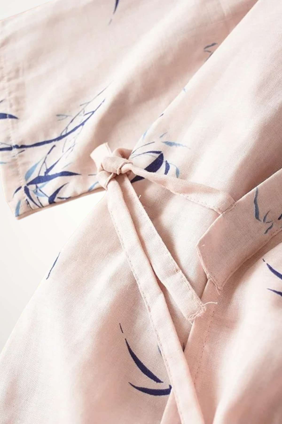 Kimono en coton rose pâle avec motifs de feuilles bleues, noué délicatement à la taille