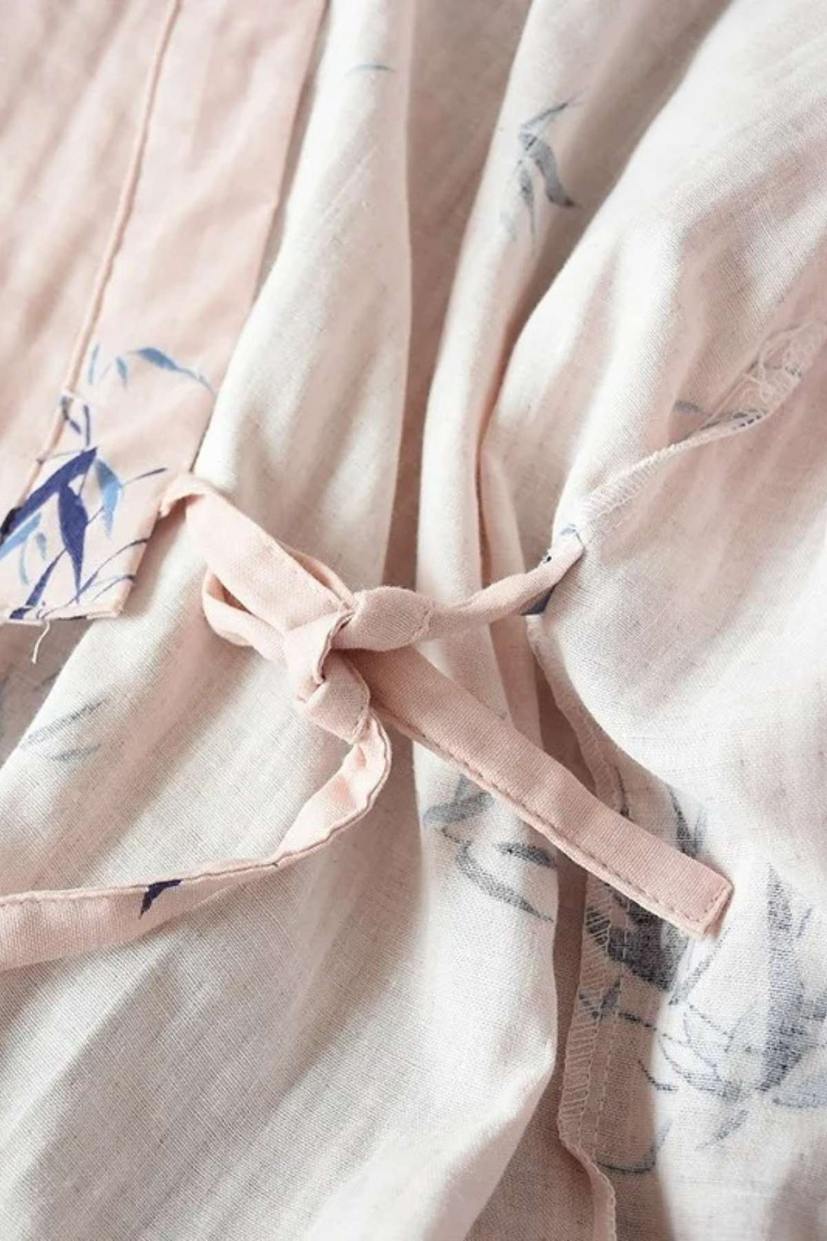 Détails d'un kimono en coton rose clair avec motifs floraux bleus et ceinture nouée délicatement