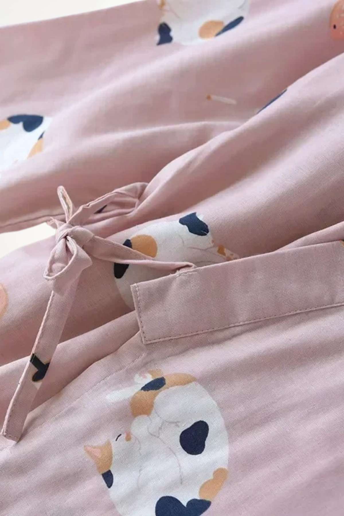 Kimono en coton rose avec motifs de chats, lien noué et texture douce, évoquant confort et style japonais