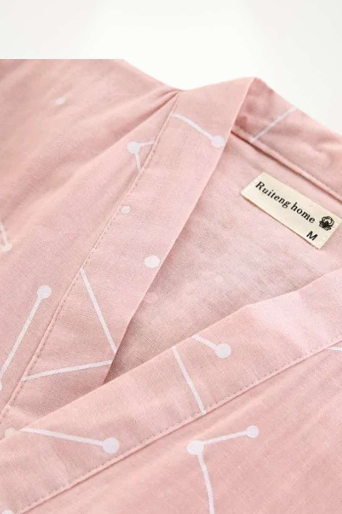 Kimono en coton rose avec motifs géométriques blancs, présentant un col ouvert et une texture douce