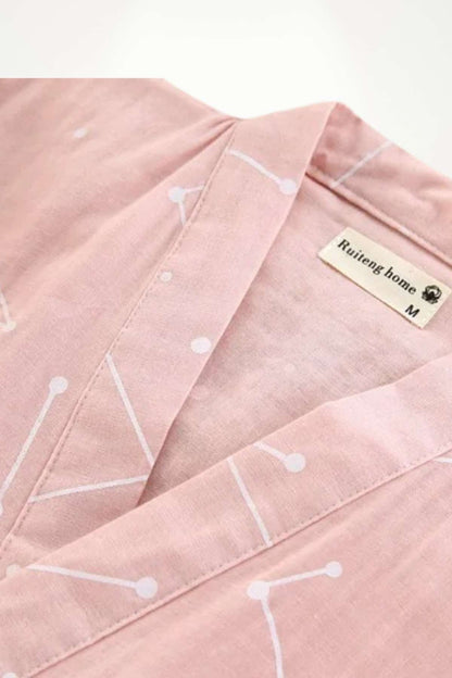Kimono en coton rose avec motifs géométriques blancs, présentant un col ouvert et une texture douce