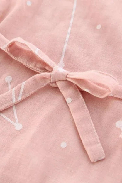 Un kimono en coton rose avec des motifs blancs et un nœud délicat au niveau de la taille