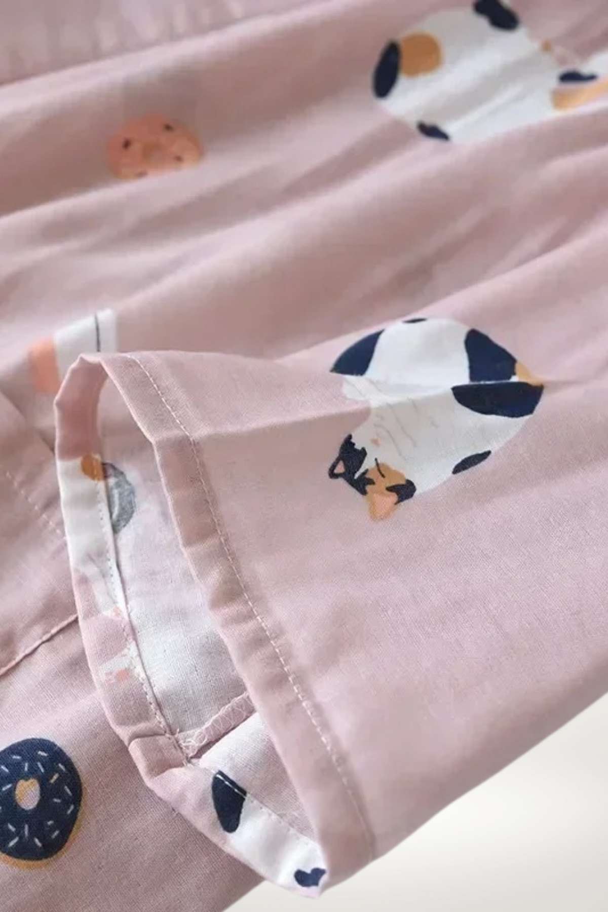Un kimono en coton rose avec des motifs de chats et de beignets, offrant un style ludique et confortable