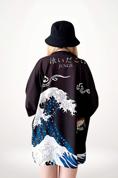 Kimono court japonais noir avec motifs de vagues bleues et blanches, porté par une femme au chapeau noir