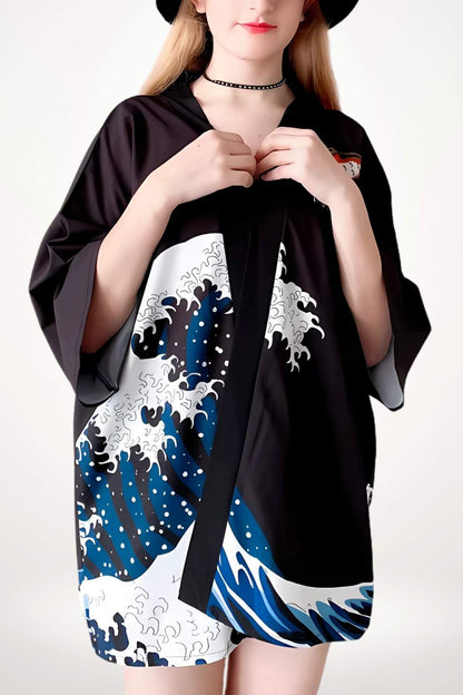 Kimono court noir avec motifs de vagues bleues et blanches, porté par une femme aux cheveux blonds