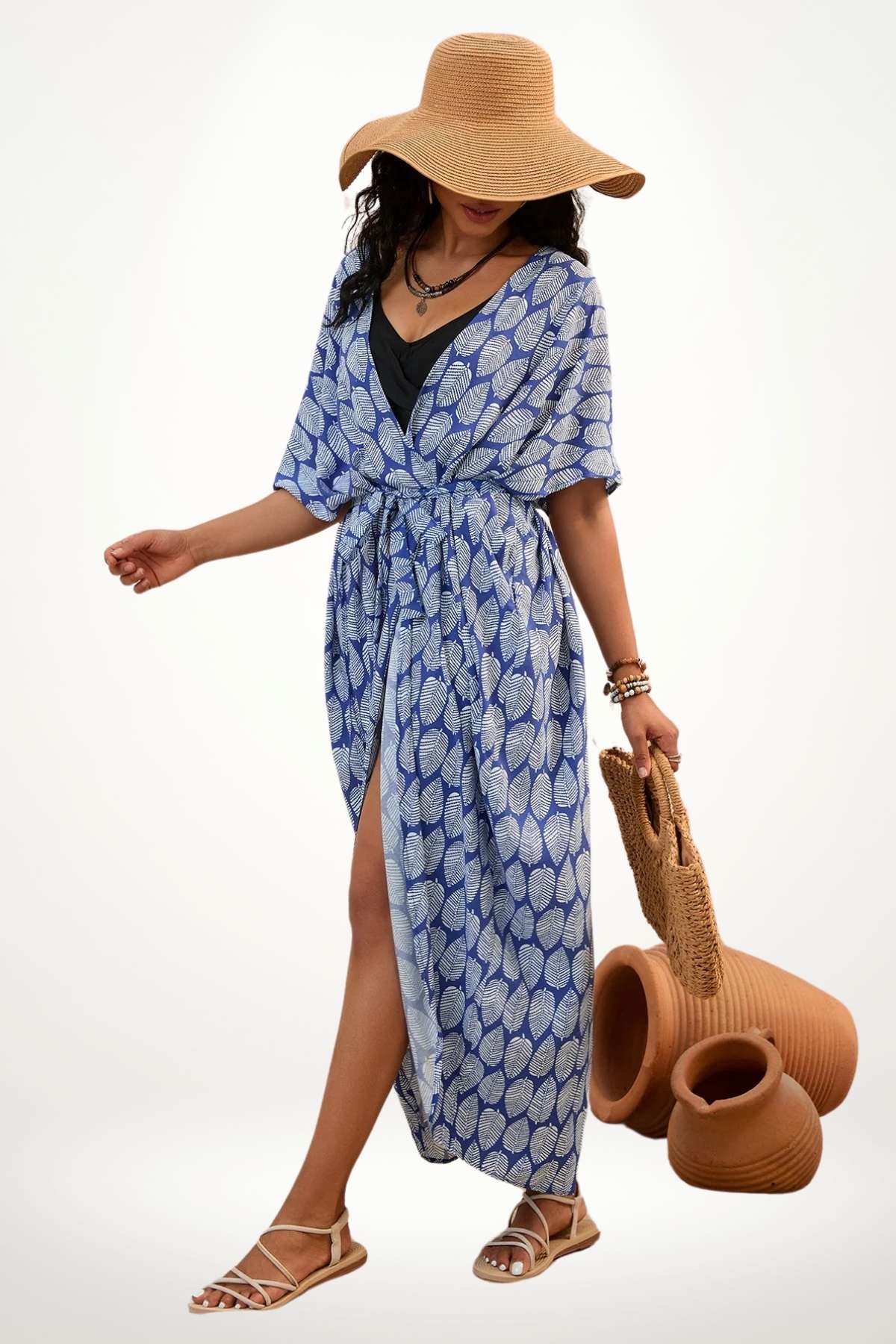 Femme portant un kimono bleu à motifs feuilles, avec un chapeau large et un sac en osier, sur fond neutre