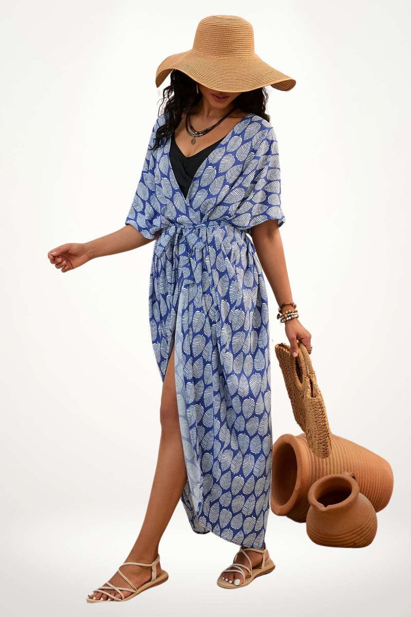 Femme portant un kimono bleu à motifs feuilles, avec un chapeau large et un sac en osier, sur fond neutre