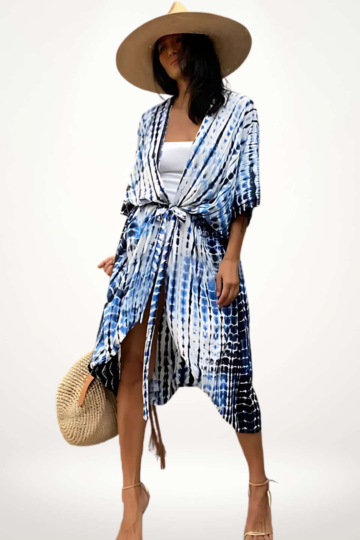 Femme portant un kimono de plage bleu et blanc, avec un chapeau large et un sac en osier