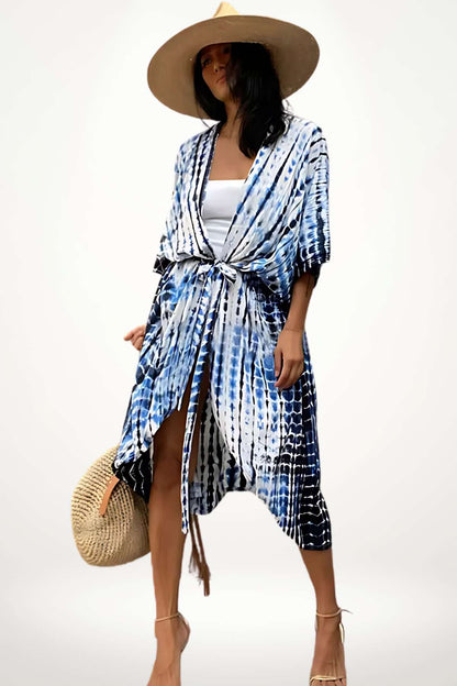 Femme portant un kimono de plage bleu et blanc, avec un chapeau large et un sac en osier