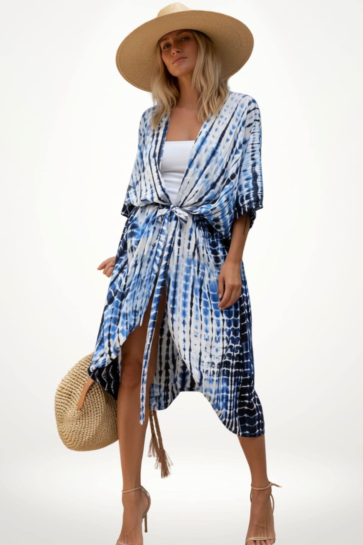 Femme portant un kimono de plage bleu et blanc, avec un chapeau large et un sac en osier