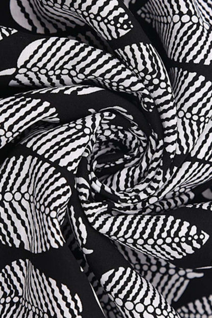 Tissu noir orné de motifs géométriques blancs, drapé avec élégance pour un kimono de plage estival