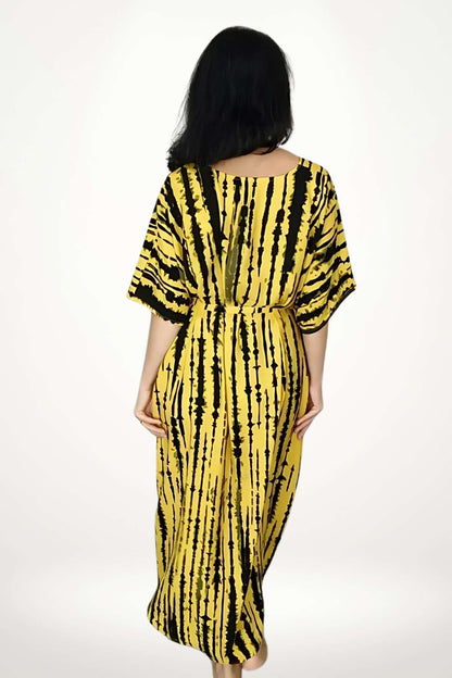 Kimono de plage aérien avec motifs rayés noirs et jaunes, porté par une femme de dos dans un décor neutre