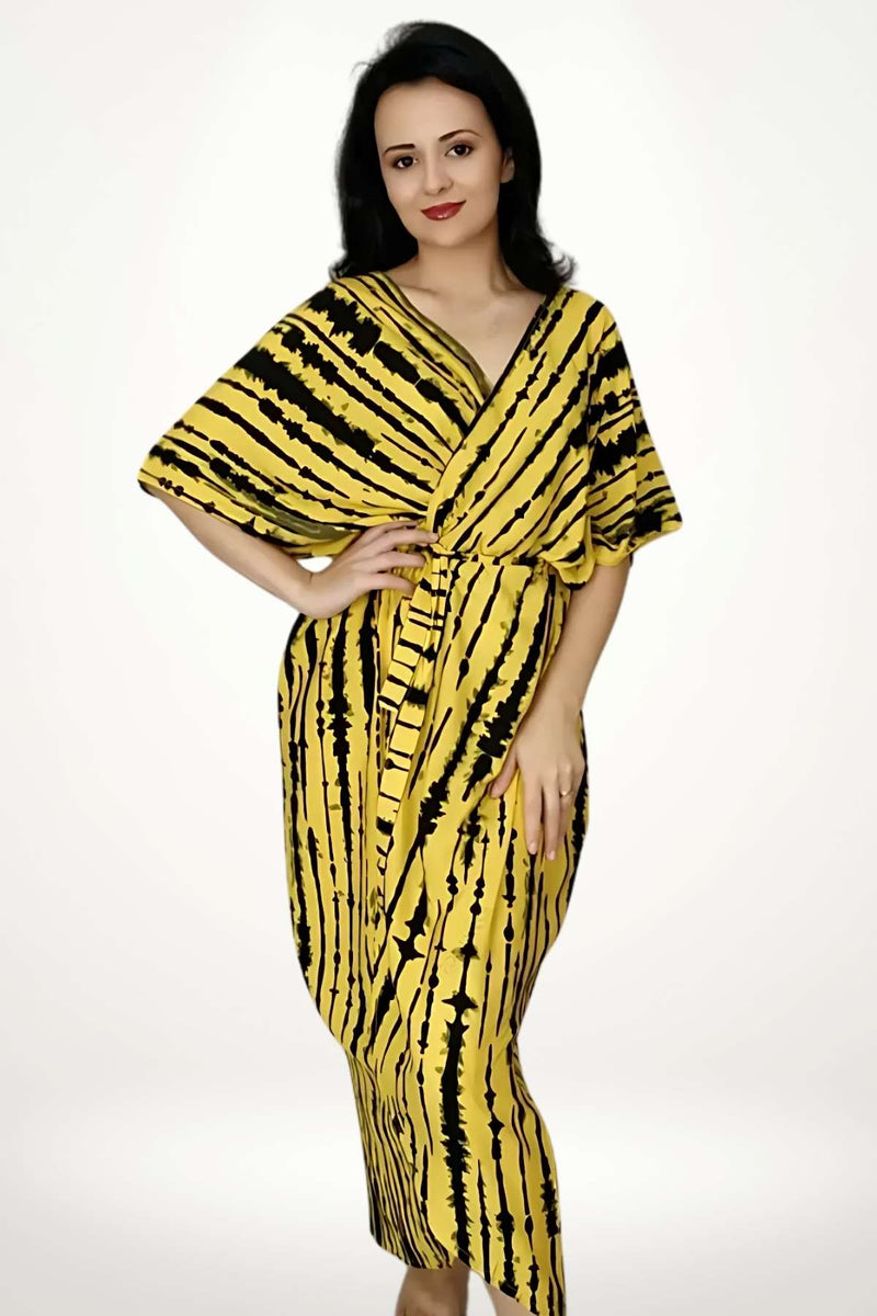 Kimono de plage en tissu jaune avec des motifs noirs, porté par une femme souriante, dans un décor neutre