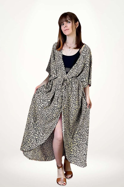 Femme en kimono à motifs léopard, debout avec un fond clair, portant des sandales brunes et un top noir