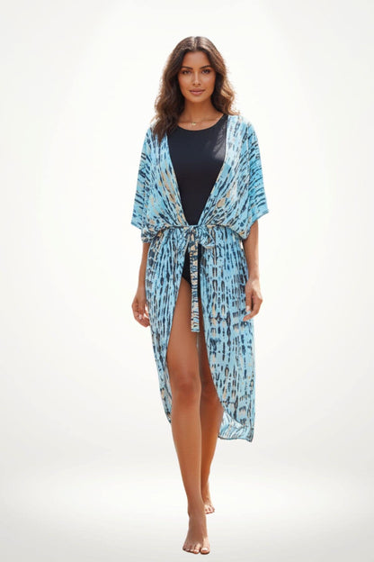 Femme portant un kimono bleu à motifs, debout sur un fond clair, avec les cheveux ondulés et un maillot noir
