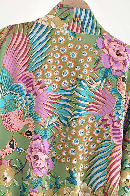 Un kimono coloré avec des motifs de paons, fleurs roses et feuilles vertes, affichant un style bohème élégant