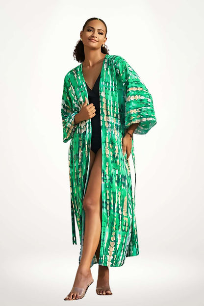 Kimono vert aux motifs abstraits, léger et fluide, porté avec un maillot de bain noir sur fond neutre
