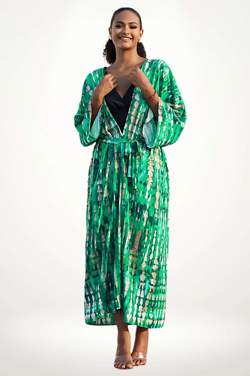 Femme souriante portant un kimono vert aux motifs fluides, dans un décor lumineux et minimaliste