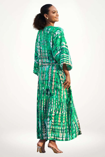 Femme souriante portant un kimono vert aux motifs fluides, dans un décor minimaliste et lumineux