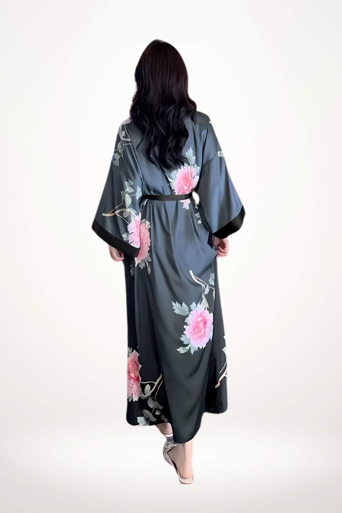 Kimono en satin noir avec des motifs floraux roses, porté par une femme aux cheveux longs, dans un décor minimaliste