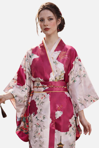 Kimono en satin rose avec motifs floraux, ceinture dorée, porté par une femme au teint clair et aux cheveux bruns