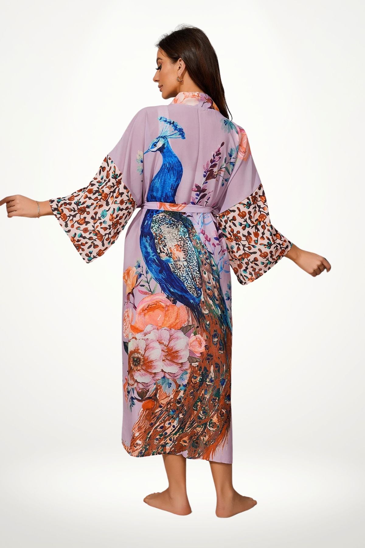 Femme en kimono satin violet orné de motifs de paons et de fleurs, debout dans un décor minimaliste